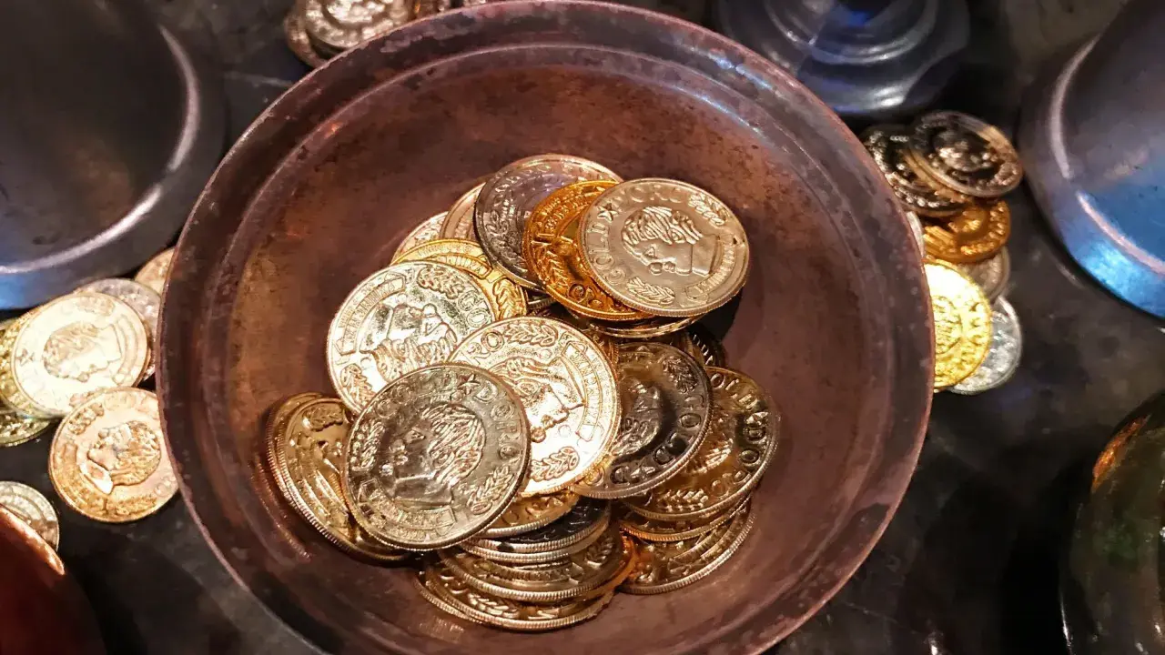 Ein Haufen goldener und silberner Schokoladenmünzen in einer Schale. Sie symbolisieren den Wert und die Bedeutung des 7. Hochzeitstages.