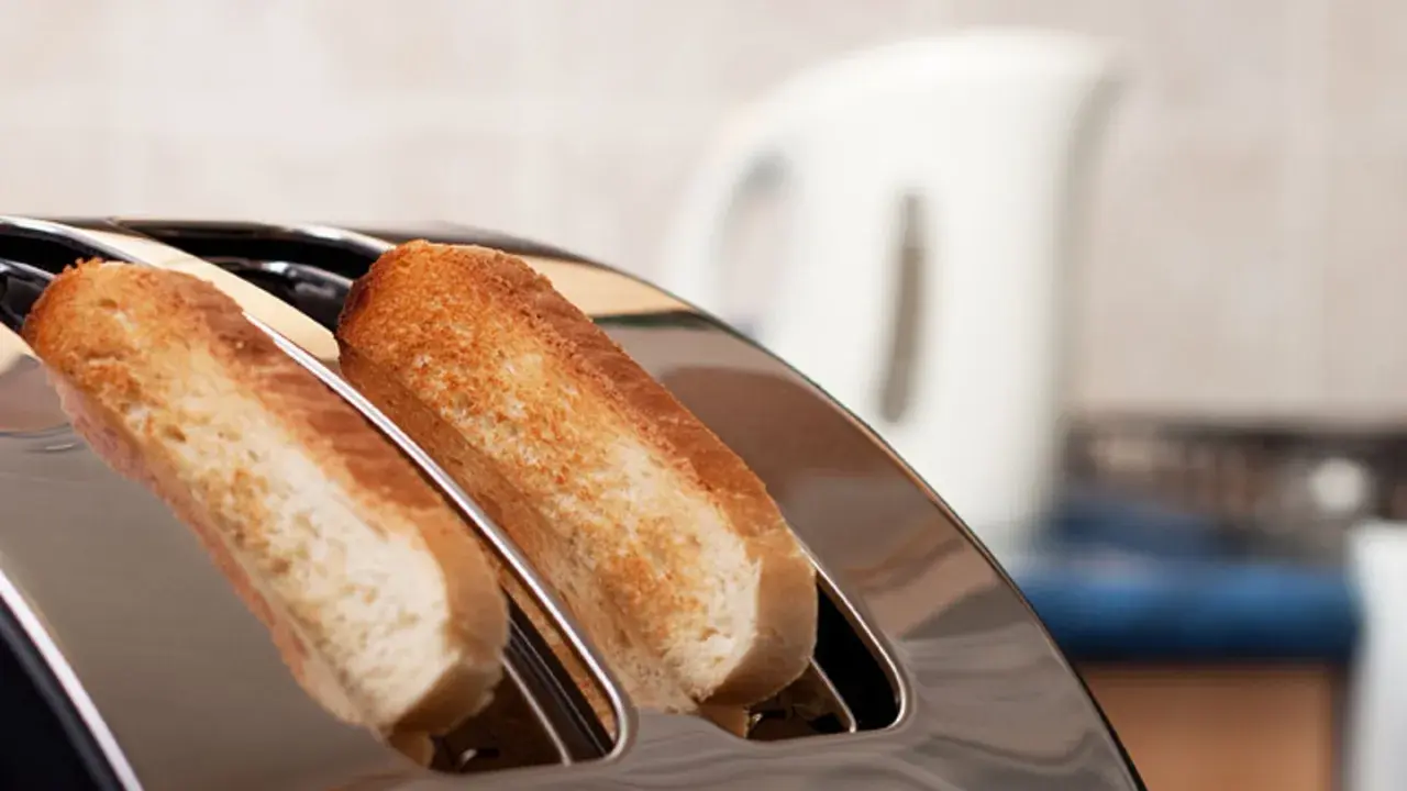 Zwei goldbraune Scheiben Toastbrot ragen aus einem glänzenden Toaster. Ein perfekter Moment, um einen Toast auszusprechen.