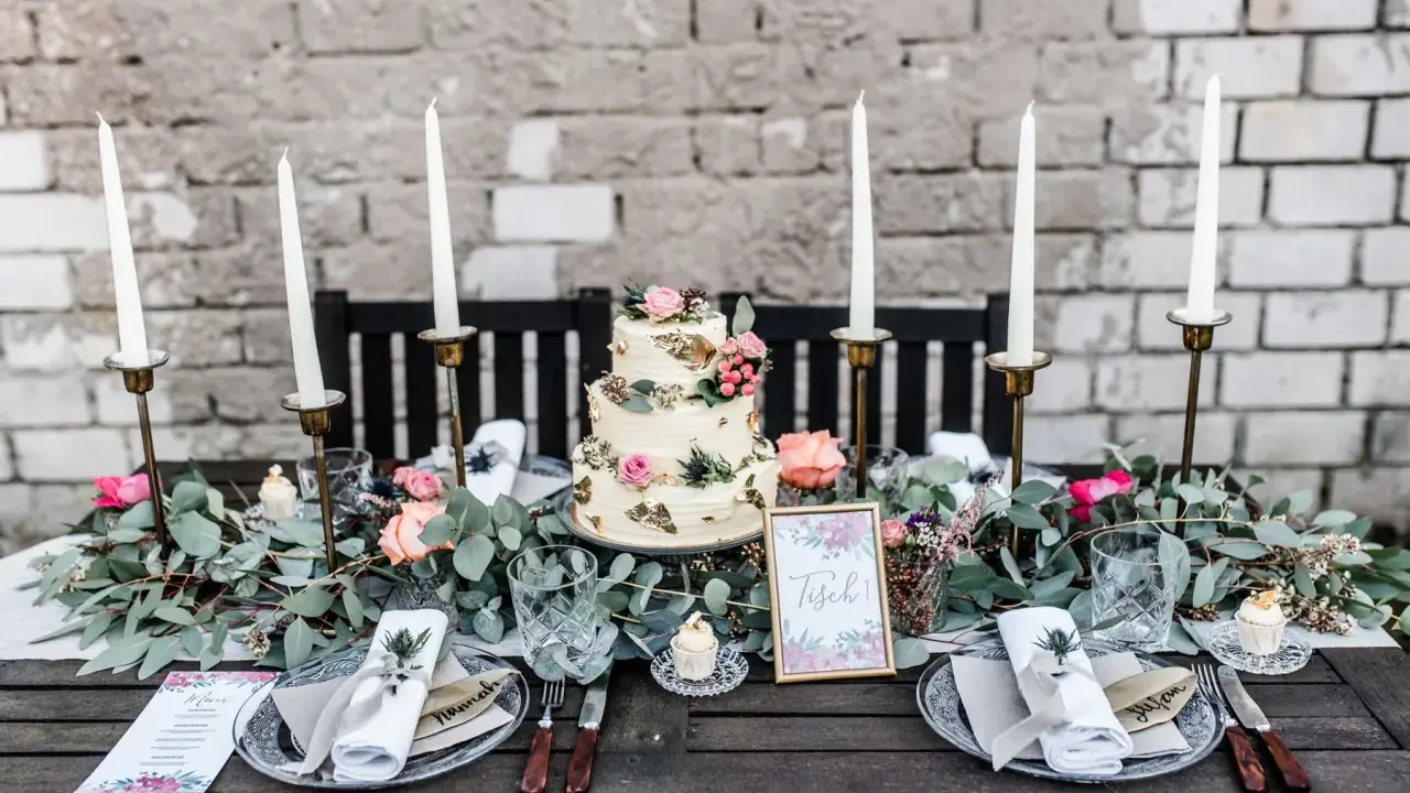 Festlich gedeckter Tisch für eine Hochzeit im Industrial Style mit dreistöckiger Torte, Kerzen und floraler Deko.