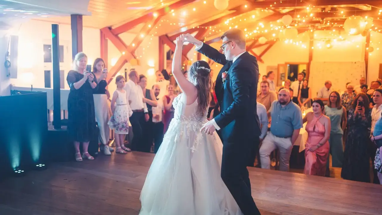 Brautpaar tanzt seinen modernen Hochzeitstanz, umgeben von Gästen und festlicher Beleuchtung.