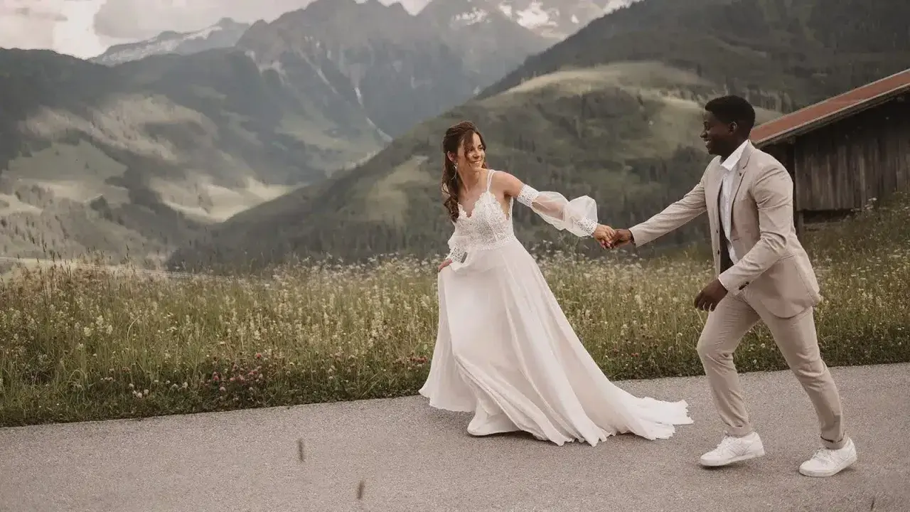 Ein glückliches Brautpaar läuft Hand in Hand vor einer Bergkulisse. Ein wunderschöner Moment für jeden weddingfilm.