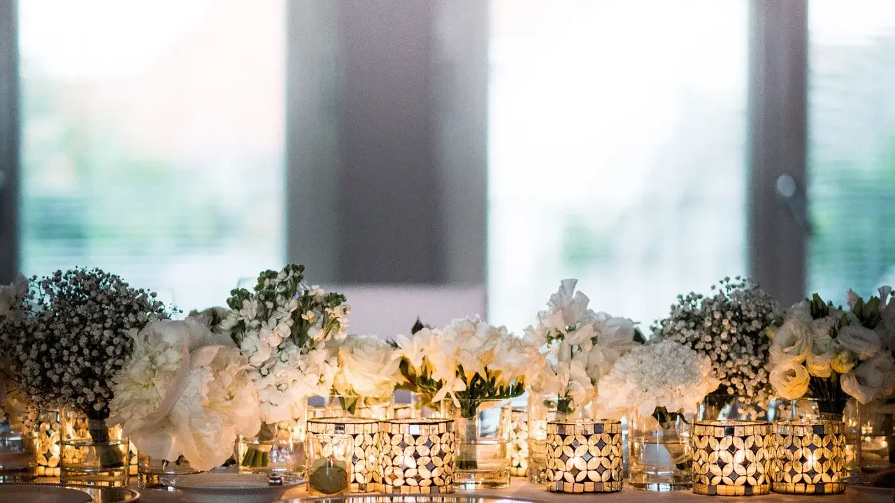 Festlich gedeckter Tisch mit weißen Blumen und Kerzen. Ein Symbol für die Bedeutung von 15 Jahren verheiratet zu sein, voller Liebe und Licht.
