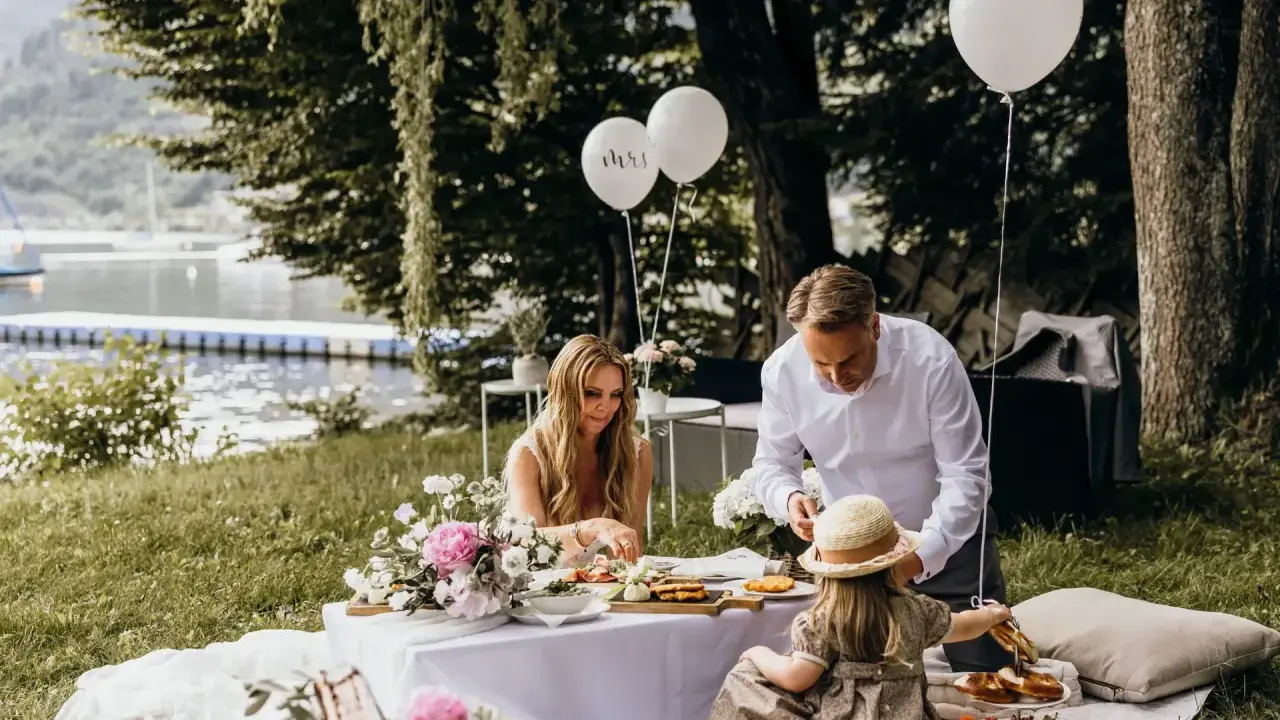 Familie feiert Hochzeit mal anders: Picknick am See mit Ballons und Blumen.