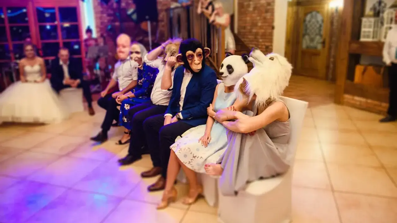 Gäste in Tiermasken warten auf kurzweilige Hochzeitsspiele. Ein Affe, ein Panda und ein weißes Tier sind zu sehen.