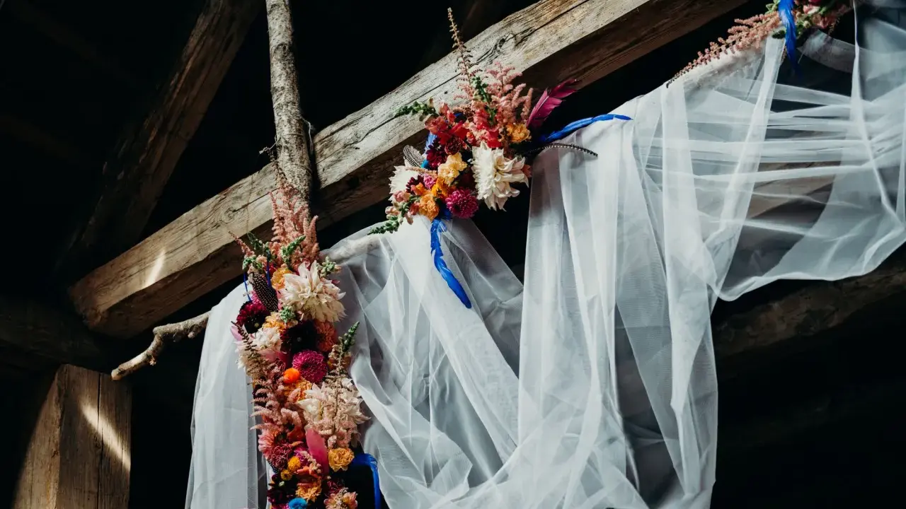 Blumenbogen mit Schleier unter Holzbalken, ein romantischer Ort für eine Feier, vielleicht zum 5 Jahre verheiratet Jubiläum.