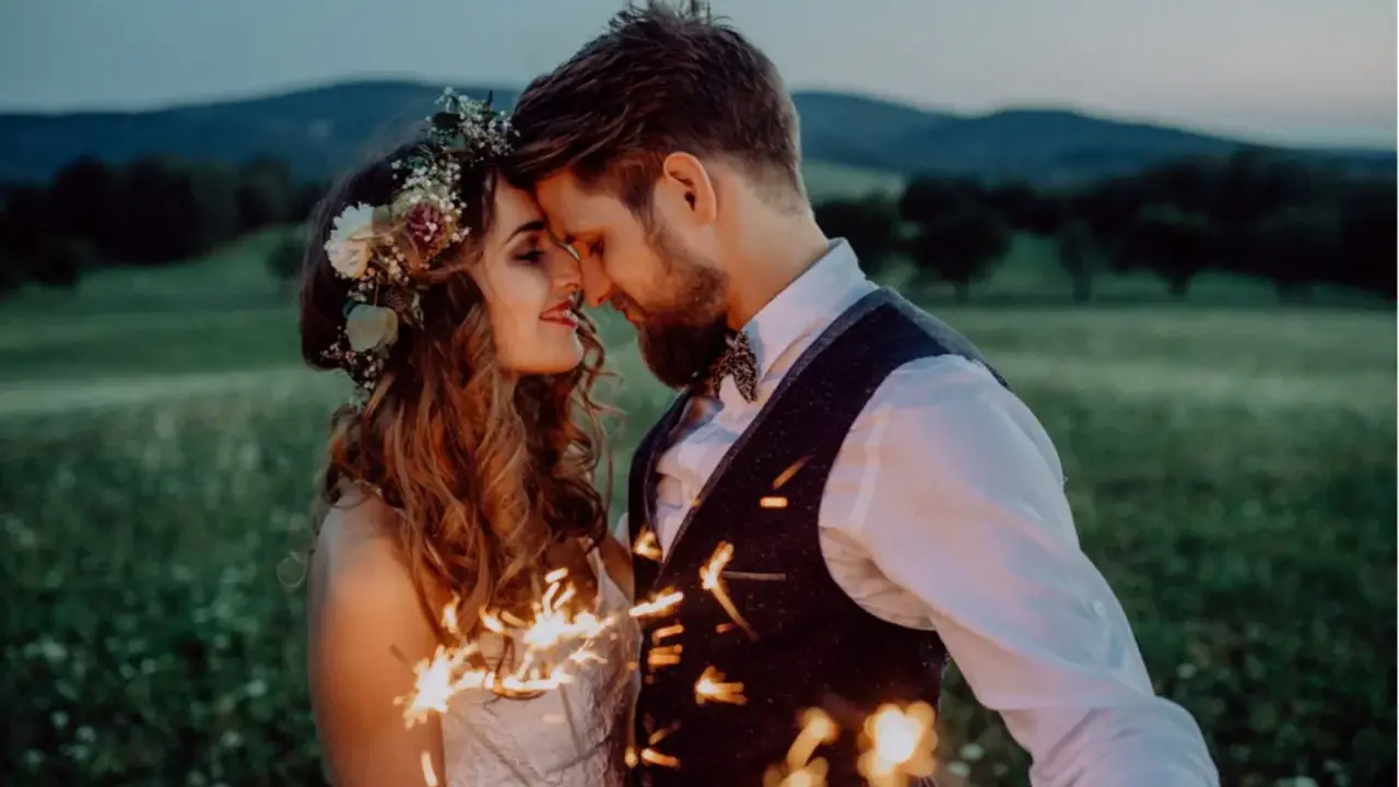 Ein Brautpaar feiert seine elopement hochzeit im Freien bei Einbruch der Dunkelheit mit Wunderkerzen.