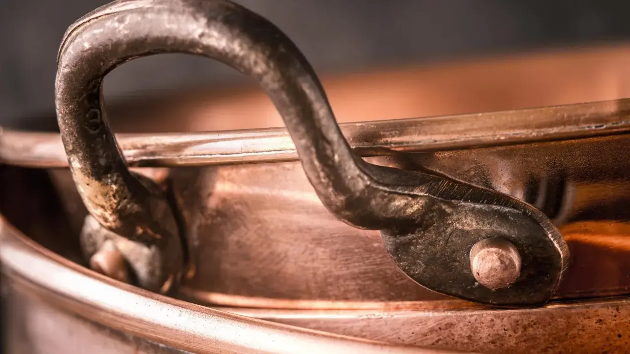 Nahaufnahme eines alten Kupferkessels mit Griff. Die Patina erzählt Geschichten, wie die **7 Jahre Ehe Bedeutung** haben, die sich in der Tiefe des Materials widerspiegelt.