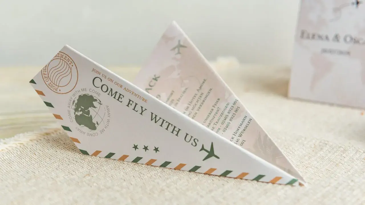 Einladung zur Hochzeit im Papierflieger-Design. Der lustige Text "Come fly with us" lädt zur gemeinsamen Reise ein.
