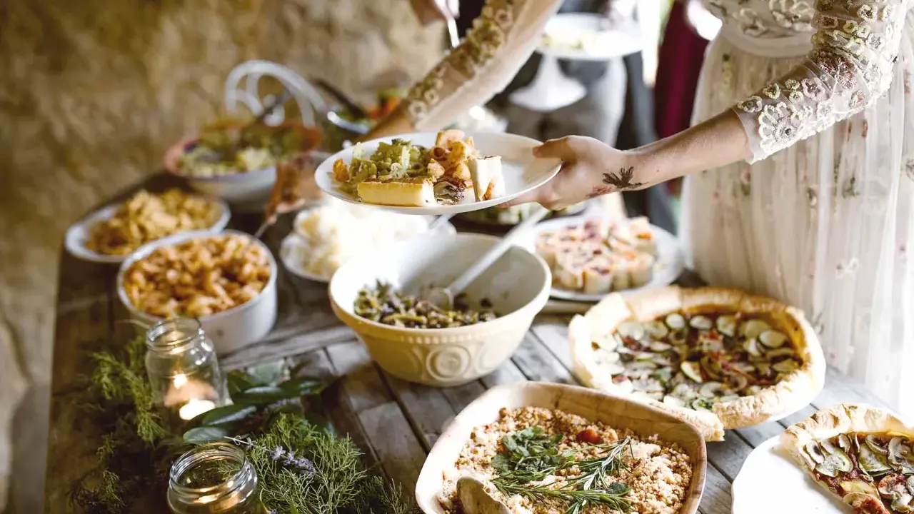 Festliches Buffet mit vielen Köstlichkeiten, perfekt für eine vegane Hochzeit. Teller werden mit leckerem Essen gefüllt.