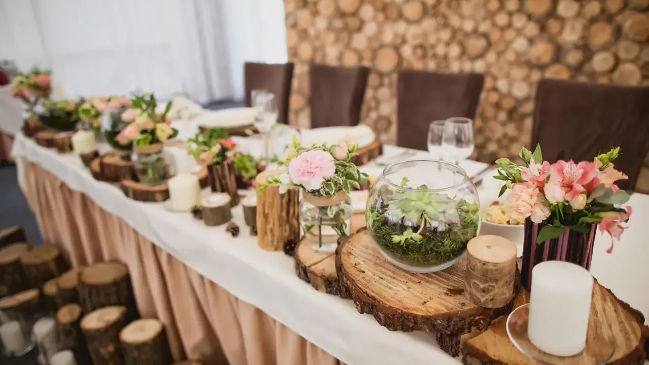 Festlich gedeckter Tisch mit Holzdeko und Blumen. Ein Terrarium und Kerzen unterstreichen die Bedeutung des 5. Hochzeitstags.