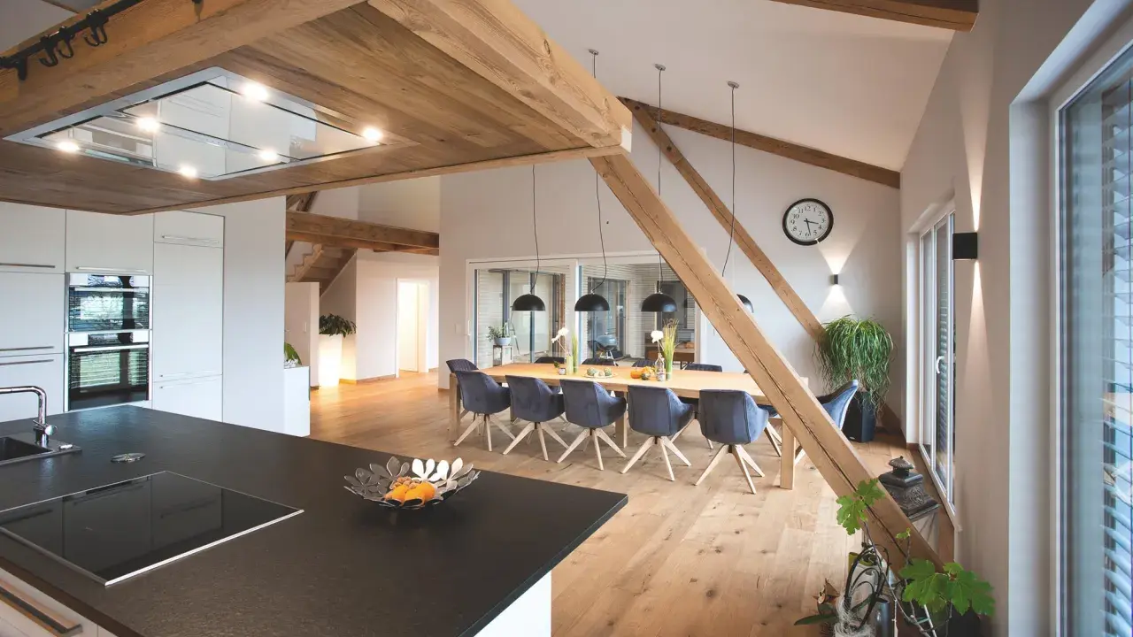 Rustikale Holzbalken und ein langer Esstisch schaffen eine gemütliche Atmosphäre, perfekt für eine Scheune Hochzeit.