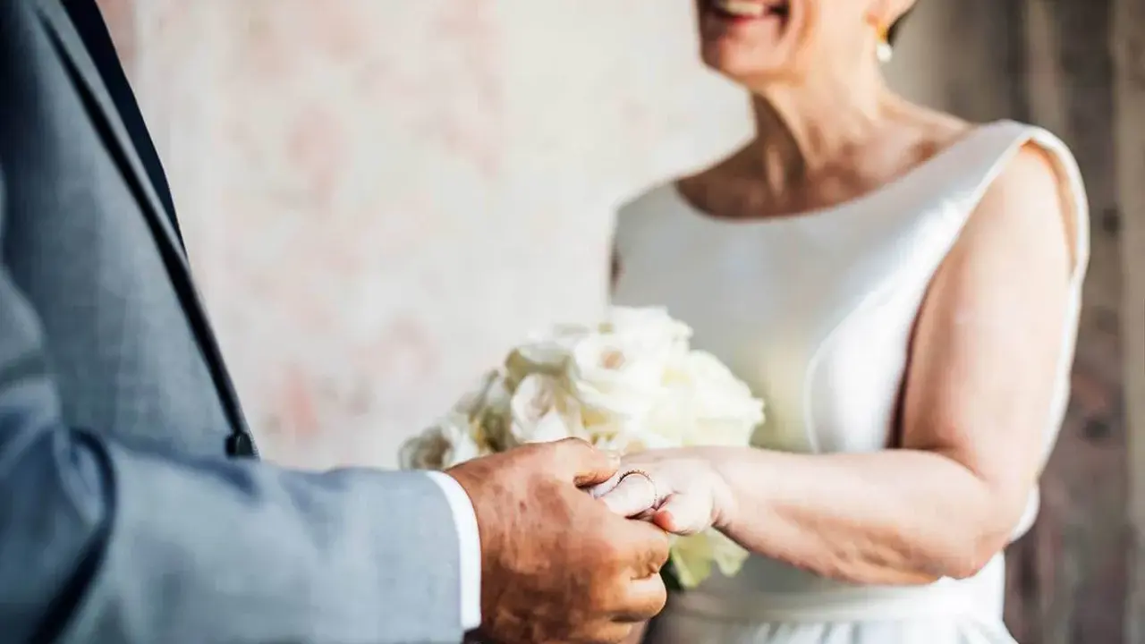 Ein glückliches Paar feiert seinen 50. Hochzeitstag. Die Bedeutung dieses Meilensteins wird durch die Ringe und den Blumenstrauß unterstrichen.