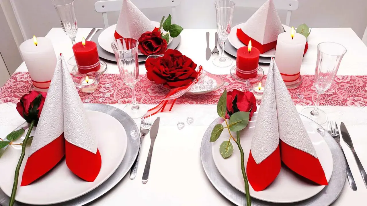 Festlich gedeckter Tisch für eine rot-weiße Hochzeit. Rote Rosen und Kerzen sorgen für romantische Stimmung.
