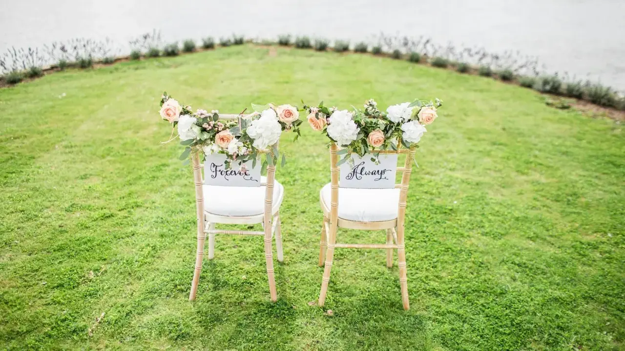 Zwei festlich geschmückte Stühle im Grünen, bereit für eine goldene Hochzeit im kleinen Kreis. "Forever" und "Always" stehen für die Ewigkeit.
