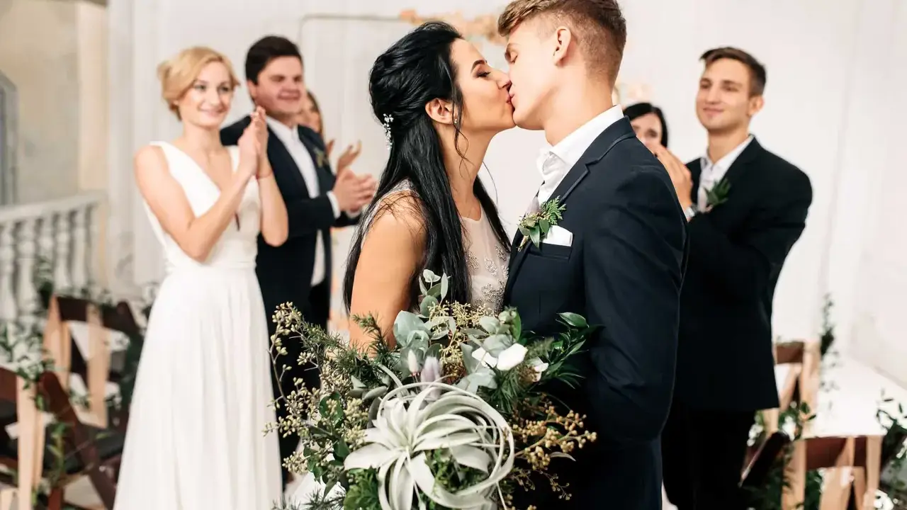 Brautpaar küsst sich, Gäste applaudieren. Der Beginn der standesamtlichen hochzeit ablauf ist ein emotionaler Moment.