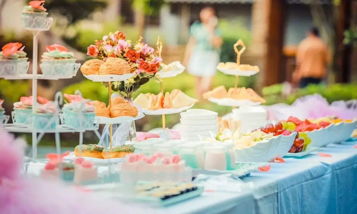 Festlich gedeckte Tafel mit Cupcakes, Gebäck, Obst und Blumen. Perfekte hochzeitsmotto ideen für ein süßes Buffet im Freien.