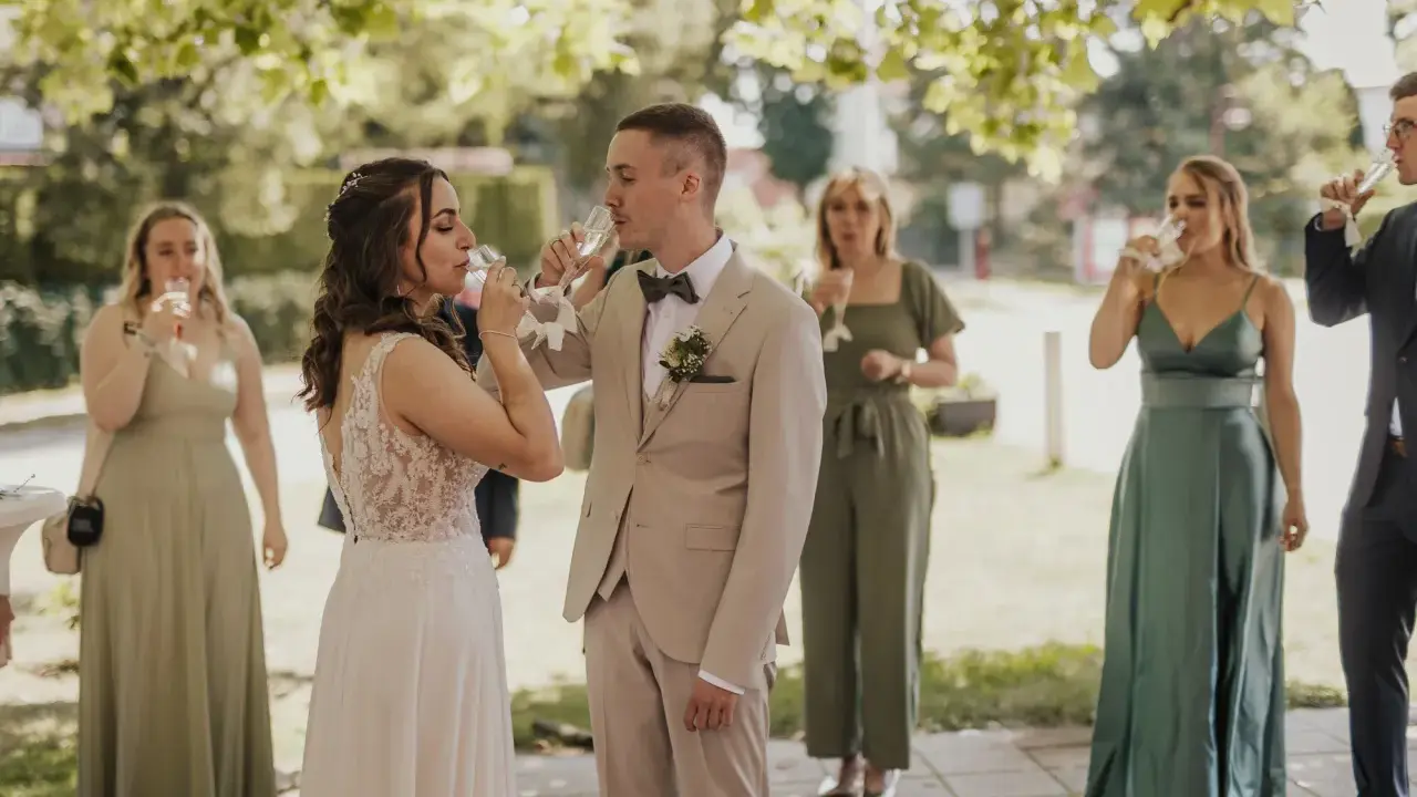 Brautpaar und Gäste stoßen beim Sekt­empfang Hochzeit an.