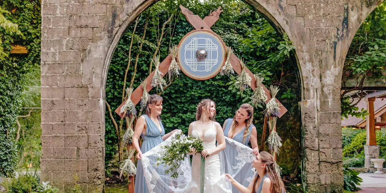 Braut und Brautjungfern unter einem Torbogen mit Wikinger-Schild. Eine stimmungsvolle Wikinger-Hochzeit.