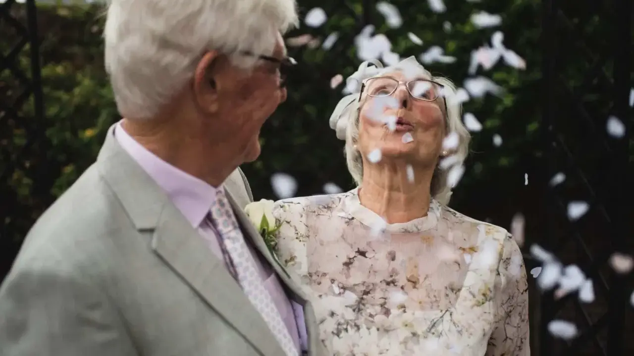 Ein glückliches Paar, meine Eltern, feiern diamantene Hochzeit. Konfetti fliegt durch die Luft, während sie sich anlächeln.