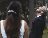 Ein Bräutigam lacht mit geschlossenen Augen in den Himmel, während die Braut ihm den Rücken zukehrt. Vielleicht ist es die Angst vor der Hochzeit, die ihn so überwältigt.