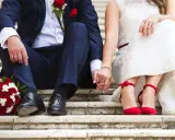 Brautpaar hält Händchen, rote Rosen und rote Schuhe. Die Frage "wie kurzfristig kann man heiraten" beschäftigt viele Paare.