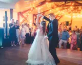 Brautpaar tanzt seinen modernen Hochzeitstanz, umgeben von Gästen und festlicher Beleuchtung.