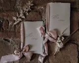 Zwei Büchlein mit zarten Bändern, auf denen "His vows" und "Her vows" steht, bereit, um Eheversprechen zu schreiben.