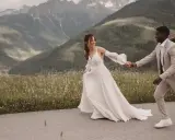Ein glückliches Brautpaar läuft Hand in Hand vor einer Bergkulisse. Ein wunderschöner Moment für jeden weddingfilm.