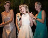 Mädchen hält Mikrofon, während ihre Schwester und andere Frauen bei einer Hochzeitsrede applaudieren.