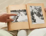 Ein älteres Paar blättert in einem Fotoalbum. Ein Finger zeigt auf ein Hochzeitsfoto. Wie viele Jahre ist die Gnadenhochzeit her?