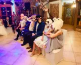 Gäste in Tiermasken warten auf kurzweilige Hochzeitsspiele. Ein Affe, ein Panda und ein weißes Tier sind zu sehen.