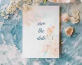 Eine Save the Date Karte mit zarten Aquarellblumen auf blauem Marmorgrund.