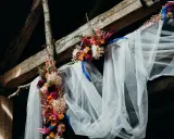 Blumenbogen mit Schleier unter Holzbalken, ein romantischer Ort für eine Feier, vielleicht zum 5 Jahre verheiratet Jubiläum.