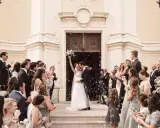 Ein strahlendes Brautpaar verlässt die Kirche, umgeben von Seifenblasen und jubelnden Gästen. Eine klassische Hochzeit voller Freude und Romantik.