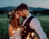 Ein Brautpaar feiert seine elopement hochzeit im Freien bei Einbruch der Dunkelheit mit Wunderkerzen.