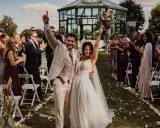 Glückliches Brautpaar feiert den Beginn des Hochzeitsablaufplans. Gäste applaudieren bei der Zeremonie im Freien.