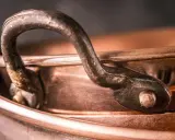Nahaufnahme eines alten Kupferkessels mit Griff. Die Patina erzählt Geschichten, wie die **7 Jahre Ehe Bedeutung** haben, die sich in der Tiefe des Materials widerspiegelt.