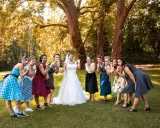 Brautjungfern in Polka-Dot-Kleidern und die Braut in Weiß posieren für eine fröhliche Rockabilly-Hochzeit im Freien.