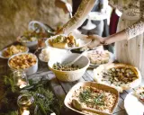 Festliches Buffet mit vielen Köstlichkeiten, perfekt für eine vegane Hochzeit. Teller werden mit leckerem Essen gefüllt.