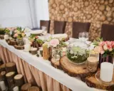 Festlich gedeckter Tisch mit Holzdeko und Blumen. Ein Terrarium und Kerzen unterstreichen die Bedeutung des 5. Hochzeitstags.
