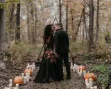 Ein Brautpaar küsst sich im Wald bei Kerzenlicht und Kürbissen. Eine romantische Halloween-Hochzeit im Herbst.
