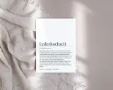 Ein Blatt Papier mit dem Text "Lederhochzeit" und einer Erklärung liegt auf einem hellen Stoff. Der Text beschreibt die Bedeutung der ledernen Hochzeit als Symbol für eine gefestigte Partnerschaft.