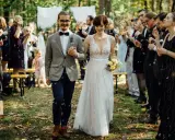 Brautpaar schreitet durch Seifenblasen, Gäste feiern Hochzeit locker.