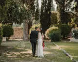 Ein Brautpaar küsst sich im Park. Die Braut trägt ein Spitzenkleid, der Bräutigam einen dunklen Anzug. Eine kroatische Hochzeit im Grünen.