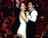 Ein glückliches Paar tanzt, umgeben von einer jubelnden Menge in Kostümen. Ein Moment, der an unvergessliche filmzitate hochzeit erinnert.