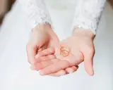 Zwei goldene Eheringe liegen in den Händen einer Braut. Sie sind ein Symbol für ihre bevorstehenden Hochzeitstage und die Namen, die sie für immer verbinden werden.