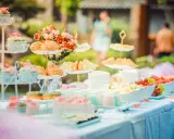 Festlich gedeckte Tafel mit Cupcakes, Gebäck, Obst und Blumen. Perfekte hochzeitsmotto ideen für ein süßes Buffet im Freien.