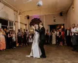 Brautpaar tanzt langsamer Walzer zu deutschen Liedern, während Gäste zusehen und fotografieren.