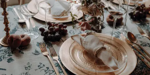 Herbstliche tischdeko hochzeit mit Trauben, Pfirsichen und goldenem Geschirr.