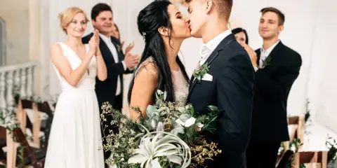 Brautpaar küsst sich, Gäste applaudieren. Der Beginn der standesamtlichen hochzeit ablauf ist ein emotionaler Moment.